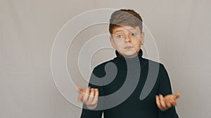 Portrait of a funny redhead and blue-eyed teenager boy showing condemnation with gestures and facial expressions on