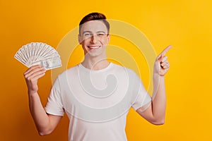 Portrait of funny reliable promoter guy hold money fan indicate finger blank space on yellow background