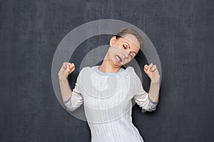 Portrait of funny and sleepy girl raising hands while yawning