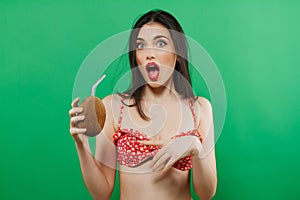 Portrait of Funny Surprised Brunette in Bright Swimwear with Tropical Cocktail in Hands on Green Background.