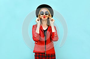 Portrait funny woman showing moustache her hair blowing red lips having fun in black round hat, red jacket on blue