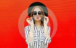 Portrait funny woman showing moustache her hair blowing red lips having fun wearing white striped shirt, black round hat over red