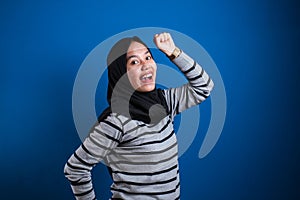 Portrait of a funny young Asian muslim girl wearing hijab dancing happily joyful expressing celebrating good news