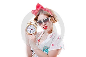 Portrait of funny young blond beautiful lady with alarm clock with glasses looking at camera