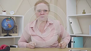 Portrait of furious senior woman pounding fist on a table. Angry Caucasian lady expressing hate as looking at camera