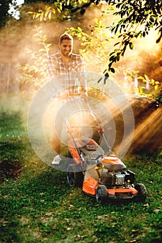 Portrait of gardener mowing the lawn using a gasoline powered device, a professional lawn mower