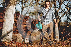 Gardener using a garden blower, clearing up leaves