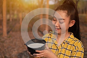 Portrait gardener young asea woman look at a full cup of raw para rubber milk of tree in plantation rubber tapping form Thailand,