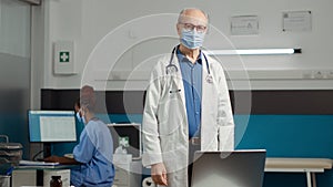 Portrait of general practitioner with face mask sitting in cabinet