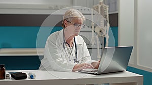 Portrait of general practitioner working on laptop in medical office