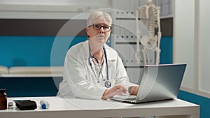 Portrait of general practitioner working on laptop in medical office