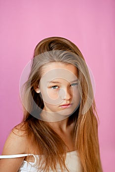 Portrait of a gentle 9-year-old long-haired girl in a light T-shirt against a lilac wall