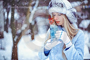 Portrait of a gentle glamorous woman in a winter hat with a winter drinkIn cold tones, snow falls, artistic toning. Concept of re