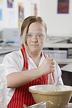 Portrait of girl (10-12) with Down syndrome mixing contents in bowl