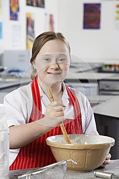 Portrait of girl (10-12) with Down syndrome mixing contents in bowl