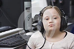 Portrait of girl (10-12) with Down syndrome wearing headphones in home recording studio