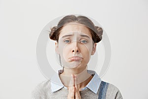 Portrait of girl 20s with upset look begging for mercy being disappointed with praying gestures. Capricious female with