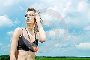 Portrait of a girl with aggressive make-up war paint indian amazon posing against the sky on nature