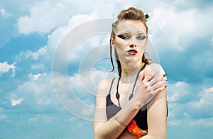 Portrait of a girl with aggressive make-up war paint indian amazon posing against the sky on nature