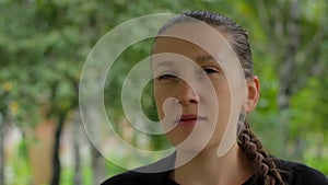 Portrait of a girl on a background of green foliage of birch trees in the summer