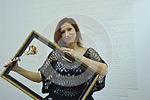 Portrait of a girl with a baguette for a picture on a white background. A young woman with a wooden rose and a frame looks at the