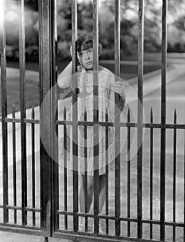 Portrait of girl through bars of fence