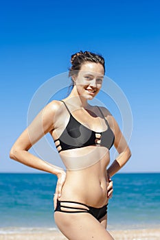 Portrait of girl in black bikini with arms akimbo