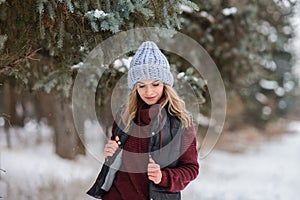 portrait of girl in a blue hat, sweater and vest, stands on a snowy winter alley