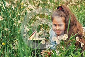 Portrait of a girl with a book among dandelions