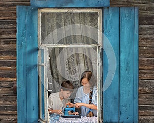 Portrait of girl and boy kids tailor sew making doll& x27;s clothes on a children& x27;s sewing machine in the window of