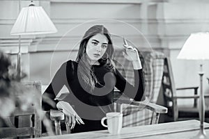 Portrait of a girl. Brunette in a coffee shop. elegant lady in a black dress, in a restaurant alone. Girl in a cafe