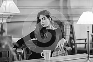 Portrait of a girl. Brunette in a coffee shop. elegant lady in a black dress, in a restaurant alone. Girl in a cafe