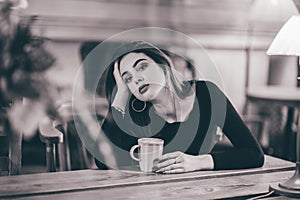 Portrait of a girl. Brunette in a coffee shop. elegant lady in a black dress, in a restaurant alone. Girl in a cafe