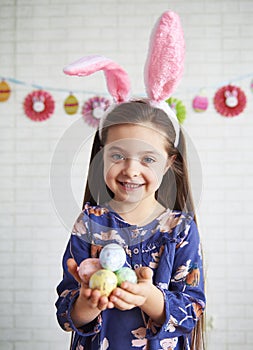 Portrait of girl with bunny ears holding colorful easter eggs