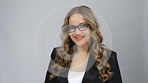 Portrait of girl in bussines suit fixing her glasses and raising eyebrow looking at camera