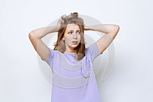 Portrait of girl in casual t shirt in panic grabbing her head in fear or frustration. Stress and mental health