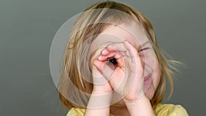 Portrait of a girl, a child makes a telescope with his hands and looks into it. The concept of adventure and thirst for