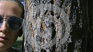 Portrait of a girl with closed eyes in glasses, leaning her head against a tree