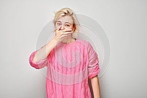 Portrait of a girl covering her mouth with hand isolated on white studio background. Bad breath concept