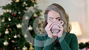 Portrait of a girl with a cup of tea in hand, woman drinking tea, looking at the camera, smiling, winter, woman in warm