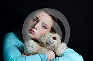 Portrait of a girl in the dark with a bear