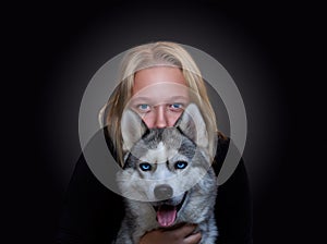 Portrait of a girl and a dog with blue eyes on a dark background
