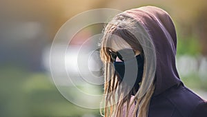 Portrait of a girl with dreadlocks in a protective medical mask. Girl in glasses and a hood