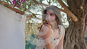 Portrait girl enjoy wind touching hair under tree. Smiling woman looking camera