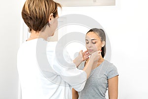 Portrait of a girl examined by a general practitioner, checking the thyroid gland and neck