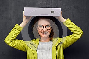Portrait of girl with eyeglasses holding big folder on head