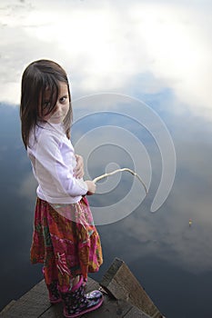 Portrait of a girl fishing in lake reflecting the sky