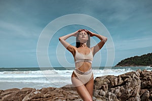 Portrait of a girl with freckles on her face and wearing beige bikini with rhinestones against the background of the