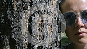 Portrait of a girl in glasses, leaning her head against a tree