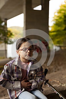 Portrait of a girl with glasses and a plaid shirt sitting on the steps of a bridge